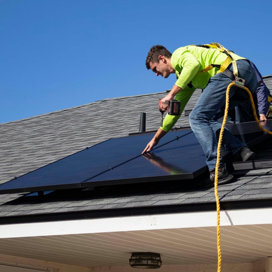 Elektriker befestigt ein Solarmodul auf einem Schrägdach