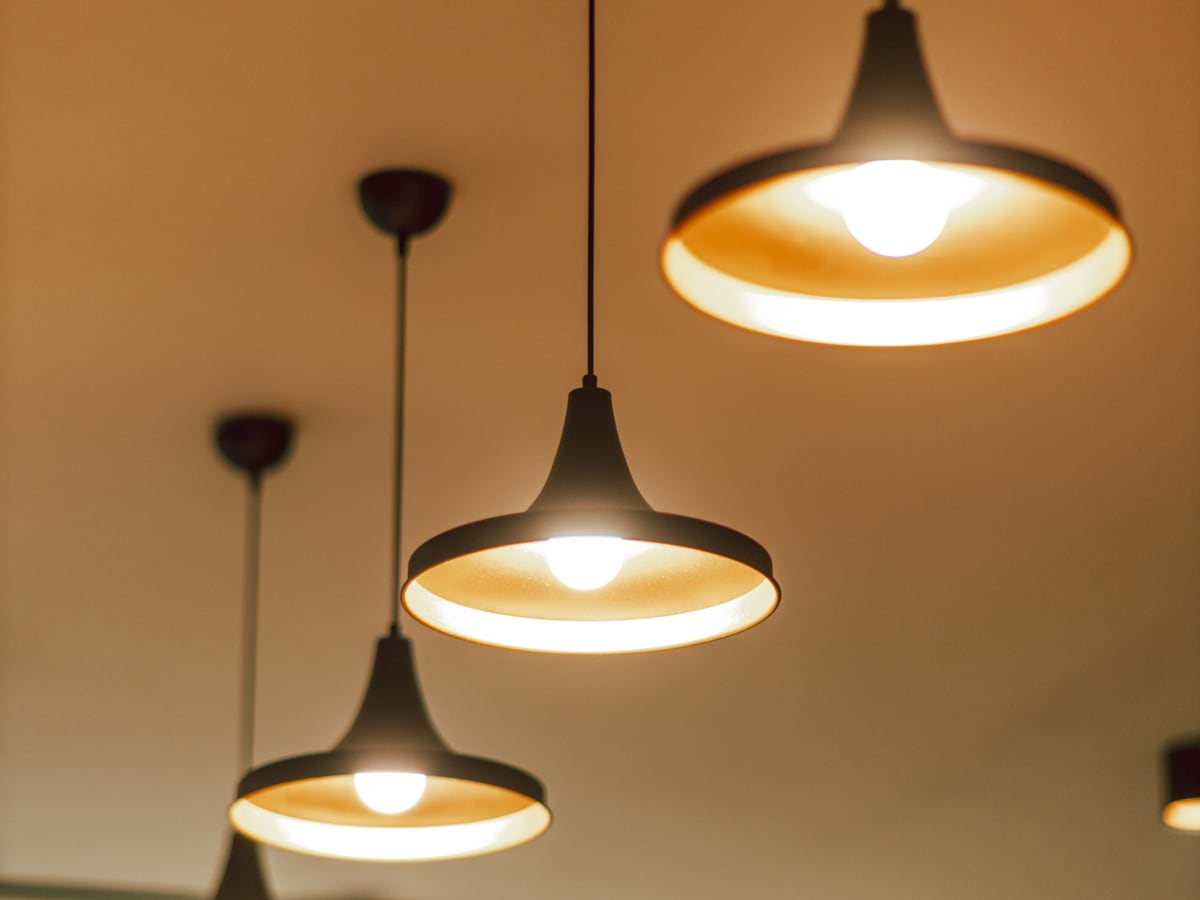 Mehrere vom Elektriker montierte Pendelleuchten geben warmes Licht an einer Decke