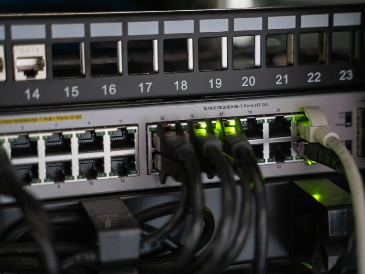 Vom Elektriker aufgelegtes Netzwerk-Patchpanel mit angeschlossenen Kabeln und aktiven Status-LEDs