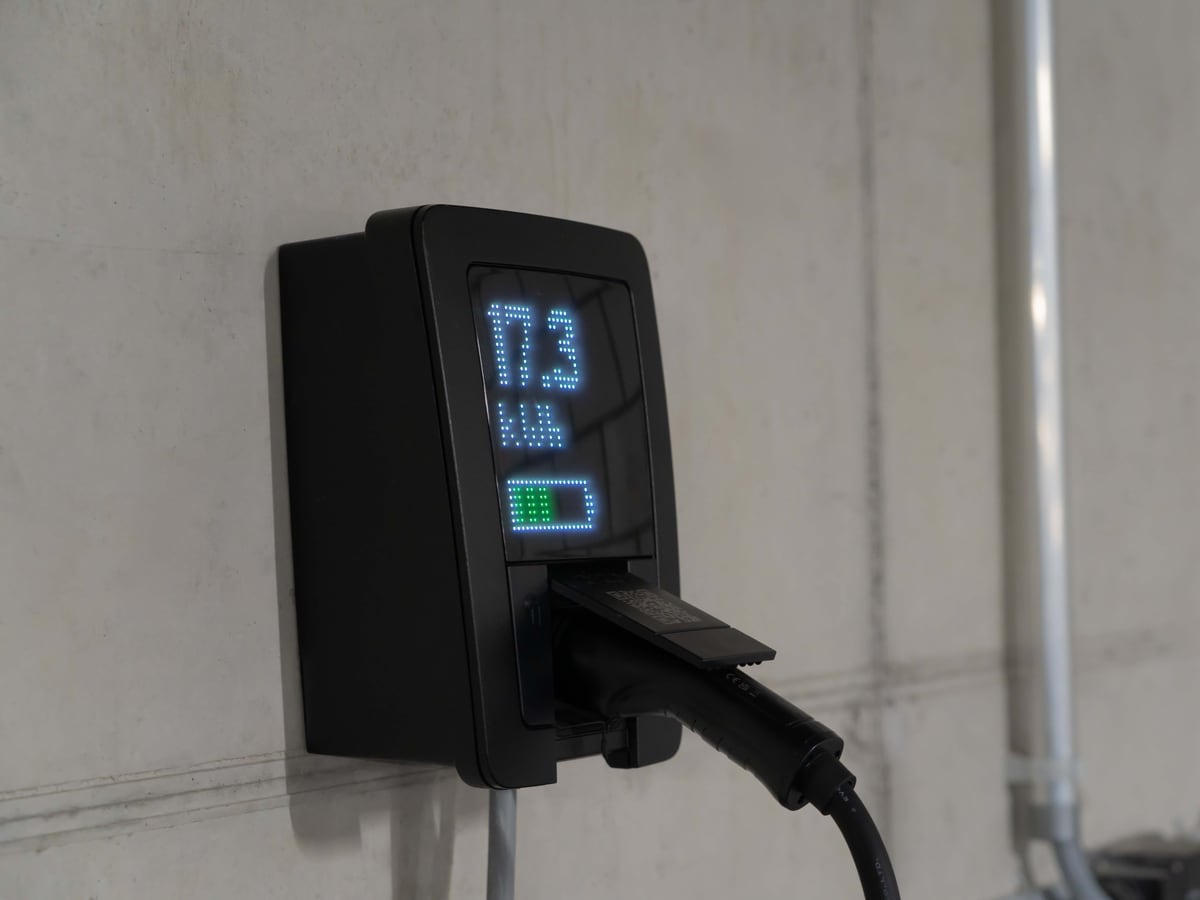 Vom Elektriker installierte Wallbox-Ladestation an einer Wand mit angeschlossenem Ladekabel